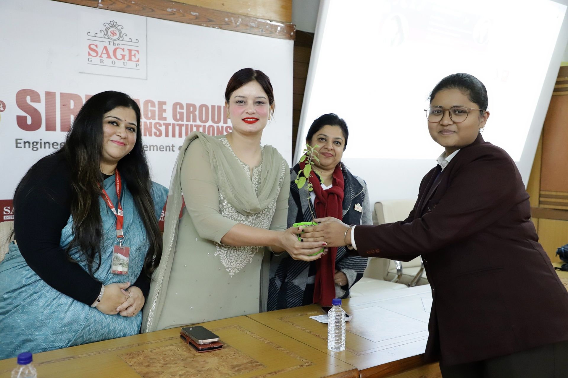Anushikha Dwivedi receiving a sapling from SAGE Group college faculty