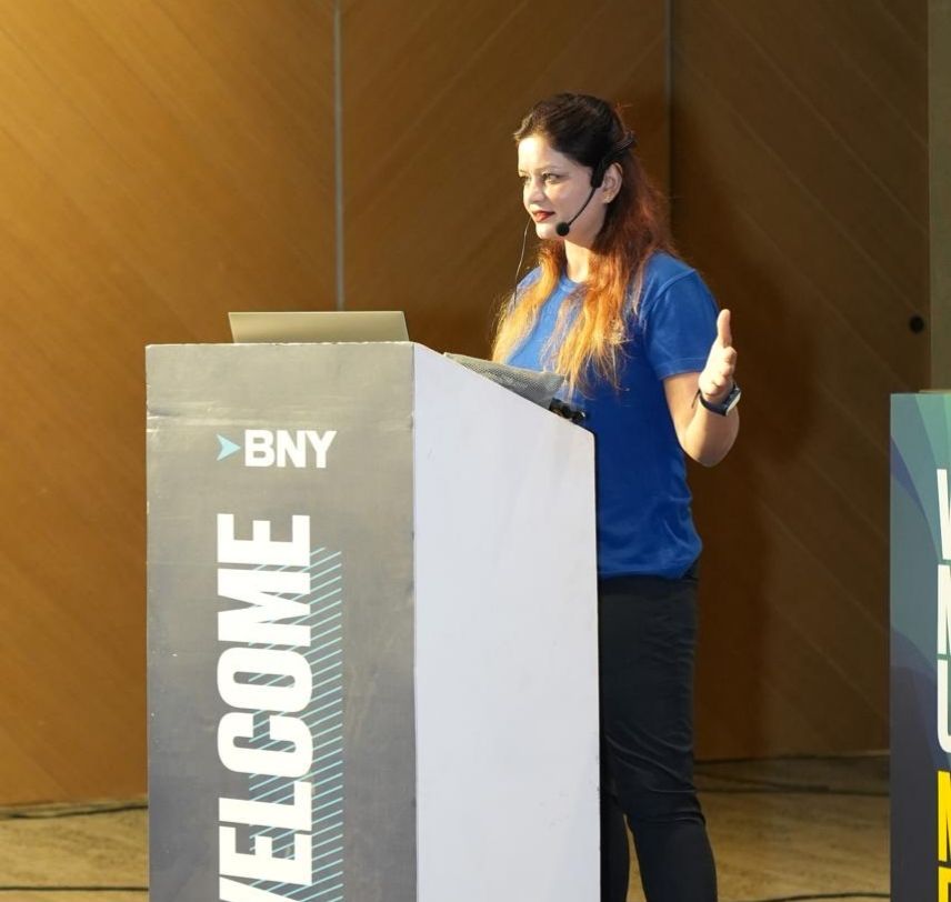 Anushikha Dwivedi speaking with a headset microphone at a BNY podium